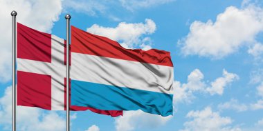 Danimarka ve Lüksemburg bayrağı birlikte beyaz bulutlu mavi gökyüzüne karşı rüzgarda sallayarak. Diplomasi kavramı, uluslararası ilişkiler.