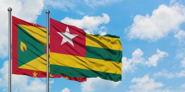 Grenada ve Togo bayrağı birlikte beyaz bulutlu mavi gökyüzüne karşı rüzgarda sallayarak. Diplomasi kavramı, uluslararası ilişkiler.