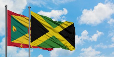 Grenada ve Jamaika bayrağı birlikte beyaz bulutlu mavi gökyüzüne karşı rüzgarda sallayarak. Diplomasi kavramı, uluslararası ilişkiler.