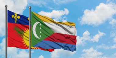 Guadeloupe ve Comoros bayrağı birlikte beyaz bulutlu mavi gökyüzüne karşı rüzgarda sallayarak. Diplomasi kavramı, uluslararası ilişkiler.