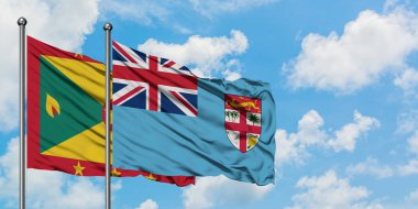 Grenada ve Fiji bayrağı birlikte beyaz bulutlu mavi gökyüzüne karşı rüzgarda sallayarak. Diplomasi kavramı, uluslararası ilişkiler.