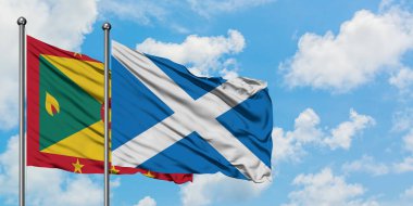 Grenada ve İskoçya bayrağı birlikte beyaz bulutlu mavi gökyüzüne karşı rüzgarda sallayarak. Diplomasi kavramı, uluslararası ilişkiler.