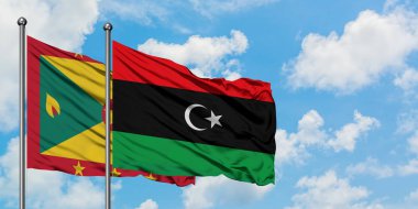 Grenada ve Libya bayrağı birlikte beyaz bulutlu mavi gökyüzüne karşı rüzgarda sallayarak. Diplomasi kavramı, uluslararası ilişkiler.