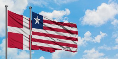 Danimarka ve Liberya bayrağı birlikte beyaz bulutlu mavi gökyüzüne karşı rüzgarda sallayarak. Diplomasi kavramı, uluslararası ilişkiler.