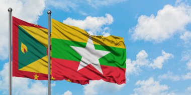 Grenada ve Myanmar bayrağı birlikte beyaz bulutlu mavi gökyüzüne karşı rüzgarda sallayarak. Diplomasi kavramı, uluslararası ilişkiler.