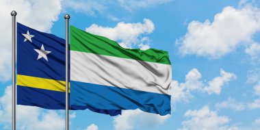Curacao ve Sierra Leone bayrağı birlikte beyaz bulutlu mavi gökyüzüne karşı rüzgarda sallayarak. Diplomasi kavramı, uluslararası ilişkiler.