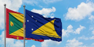 Grenada ve Tokelau bayrağı birlikte beyaz bulutlu mavi gökyüzüne karşı rüzgarda sallayarak. Diplomasi kavramı, uluslararası ilişkiler.