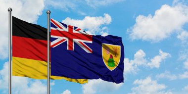 Almanya ve Turks ve Caicos Adaları bayrağı havada sallayarak beyaz bulutlu mavi gökyüzüne karşı birlikte. Diplomasi kavramı, uluslararası ilişkiler.