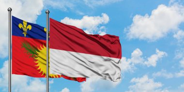 Guadeloupe ve Monako bayrağı birlikte beyaz bulutlu mavi gökyüzüne karşı rüzgarda sallayarak. Diplomasi kavramı, uluslararası ilişkiler.