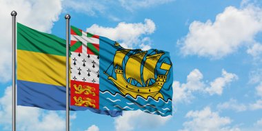 Gabon ve Saint Pierre ve Miquelon bayrağı birlikte beyaz bulutlu mavi gökyüzüne karşı rüzgarda sallayarak. Diplomasi kavramı, uluslararası ilişkiler.