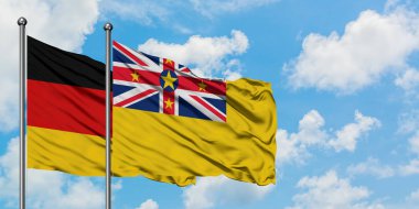 Almanya ve Niue bayrağı birlikte beyaz bulutlu mavi gökyüzüne karşı rüzgarda sallayarak. Diplomasi kavramı, uluslararası ilişkiler.