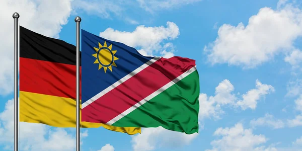 Germania e Namibia sventolano nel vento contro il bianco cielo azzurro nuvoloso insieme. Concetto di diplomazia, relazioni internazionali . — Foto Stock