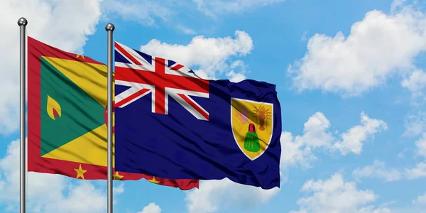 Bandera de Granada y las Islas Turcas y Caicos ondeando en el viento contra el cielo azul nublado blanco juntos. Concepto diplomático, relaciones internacionales . — Foto de Stock