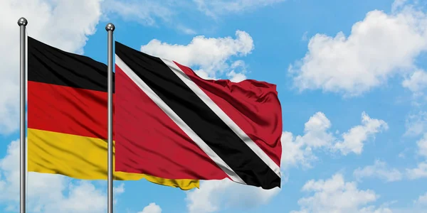 Allemagne et Trinité-et-Tobago drapeau agitant dans le vent contre ciel bleu nuageux blanc ensemble. Concept de diplomatie, relations internationales . — Photo