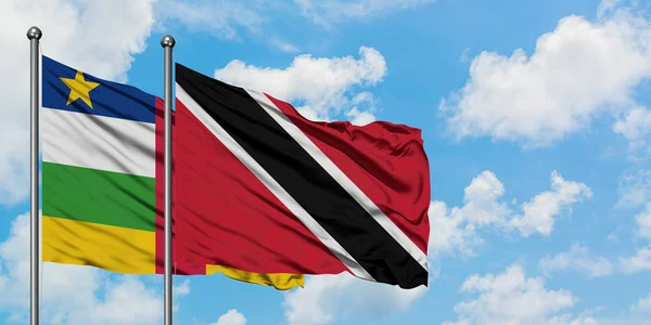Bandera de la República Centroafricana y Trinidad y Tobago ondeando en el viento contra el cielo azul nublado blanco juntos. Concepto diplomático, relaciones internacionales . — Foto de Stock