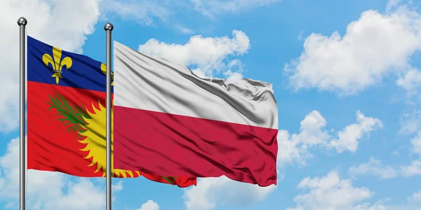 Guadalupe y la bandera de Polonia ondeando en el viento contra el cielo azul nublado blanco juntos. Concepto diplomático, relaciones internacionales . — Foto de Stock