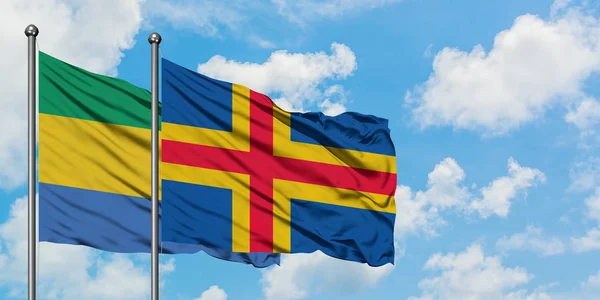 Gabon and Aland Islands flag waving in the wind against white cloudy blue sky together. Diplomacy concept, international relations. — Stock Photo, Image