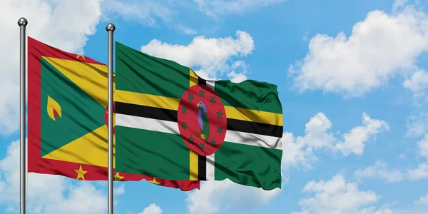 Grenada e Dominica sventolano nel vento contro il bianco cielo blu nuvoloso insieme. Concetto di diplomazia, relazioni internazionali . — Foto Stock