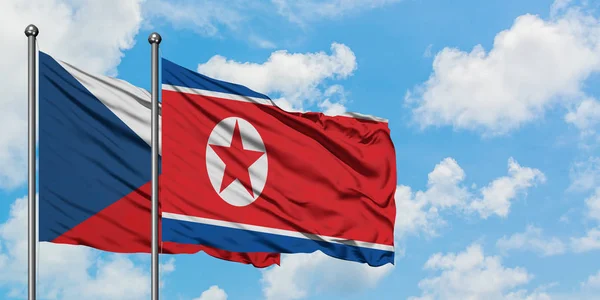 Bandera de República Checa y Corea del Norte ondeando en el viento contra el cielo azul nublado blanco juntos. Concepto diplomático, relaciones internacionales . — Foto de Stock