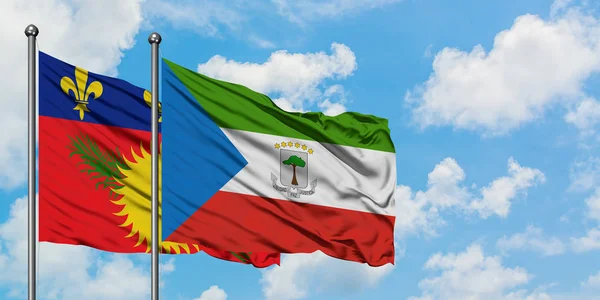 Guadalupe y Guinea Ecuatorial ondeando en el viento contra el cielo azul nublado blanco juntos. Concepto diplomático, relaciones internacionales . — Foto de Stock