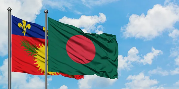 Guadalupe y la bandera de Bangladesh ondeando en el viento contra el cielo azul nublado blanco juntos. Concepto diplomático, relaciones internacionales . — Foto de Stock