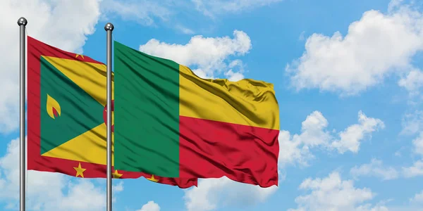 Bandera de Granada y Benín ondeando en el viento contra el cielo azul nublado blanco juntos. Concepto diplomático, relaciones internacionales . — Foto de Stock