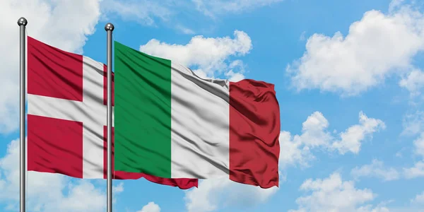Bandera de Dinamarca e Italia ondeando en el viento contra el cielo azul nublado blanco juntos. Concepto diplomático, relaciones internacionales . — Foto de Stock