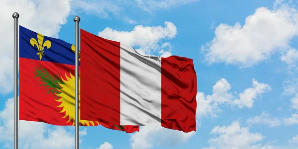 Guadalupe y la bandera del Perú ondeando en el viento contra el cielo azul nublado blanco juntos. Concepto diplomático, relaciones internacionales . — Foto de Stock