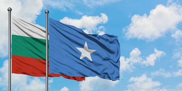 Bandera de Bulgaria y Somalia ondeando en el viento contra el cielo azul nublado blanco juntos. Concepto diplomático, relaciones internacionales . — Foto de Stock
