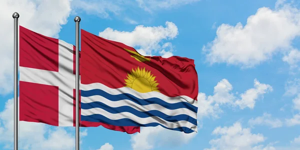 Bandera de Dinamarca y Kiribati ondeando en el viento contra el cielo azul nublado blanco juntos. Concepto diplomático, relaciones internacionales . — Foto de Stock