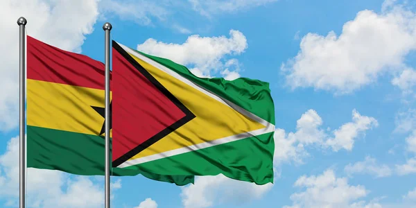 Ghana e Guyana sventolano nel vento contro il bianco cielo blu nuvoloso insieme. Concetto di diplomazia, relazioni internazionali . — Foto Stock