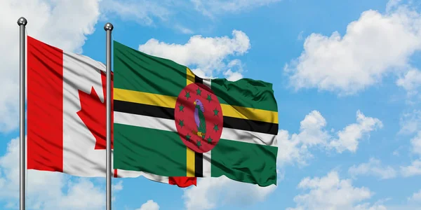 Bandera de Canadá y Dominica ondeando en el viento contra el cielo azul nublado blanco juntos. Concepto diplomático, relaciones internacionales . — Foto de Stock