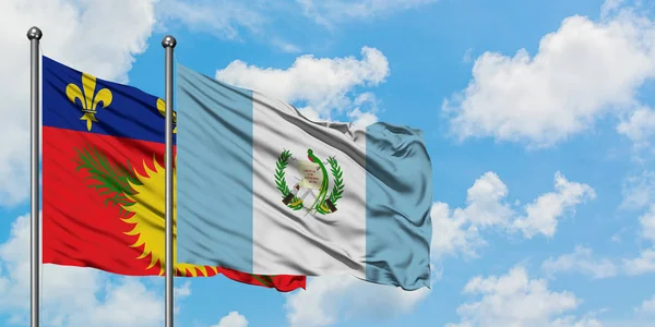 Guadalupe y la bandera de Guatemala ondeando en el viento contra el cielo azul nublado blanco juntos. Concepto diplomático, relaciones internacionales . — Foto de Stock
