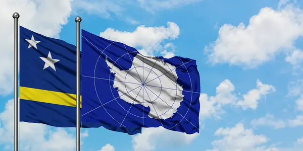 Bendera Curacao dan Antarktika melambaikan tangan dalam angin melawan langit biru berawan putih bersama-sama. Konsep diplomasi, hubungan internasional . — Stok Foto