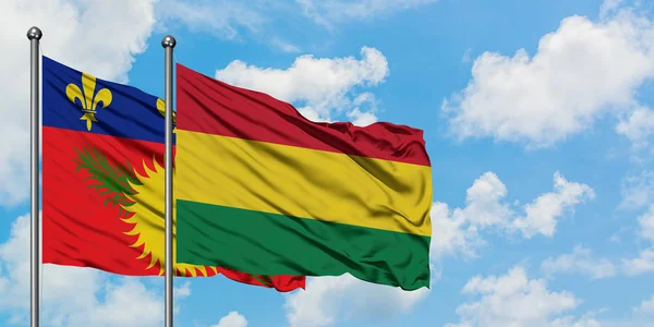 Bandera de Guadalupe y Bolivia ondeando en el viento contra el cielo azul nublado blanco juntos. Concepto diplomático, relaciones internacionales . — Foto de Stock