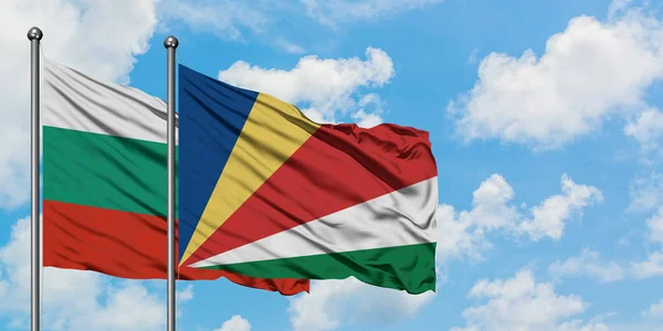 Bandera de Bulgaria y Seychelles ondeando en el viento contra el cielo azul nublado blanco juntos. Concepto diplomático, relaciones internacionales . — Foto de Stock