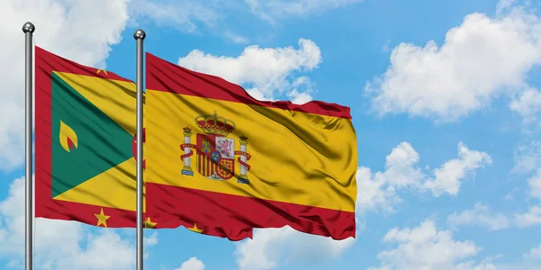 Grenada e la Spagna bandiera sventolando nel vento contro bianco cielo blu nuvoloso insieme. Concetto di diplomazia, relazioni internazionali . — Foto Stock