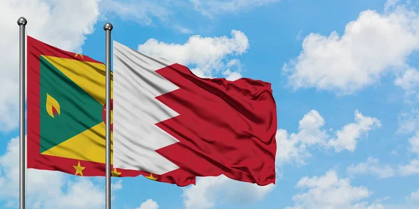 Bandera de Granada y Bahréin ondeando en el viento contra el cielo azul nublado blanco juntos. Concepto diplomático, relaciones internacionales . — Foto de Stock