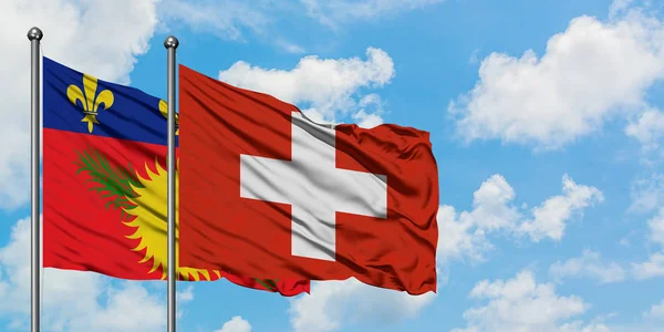 Гваделупа и швейцарский флаг вместе размахивают ветром против белого облачно-голубого неба. Концепция дипломатии, международные отношения . — стоковое фото