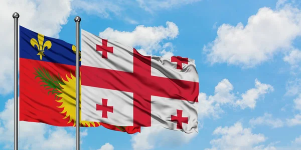 Guadalupe y la bandera de Georgia ondeando en el viento contra el blanco cielo azul nublado juntos. Concepto diplomático, relaciones internacionales . — Foto de Stock