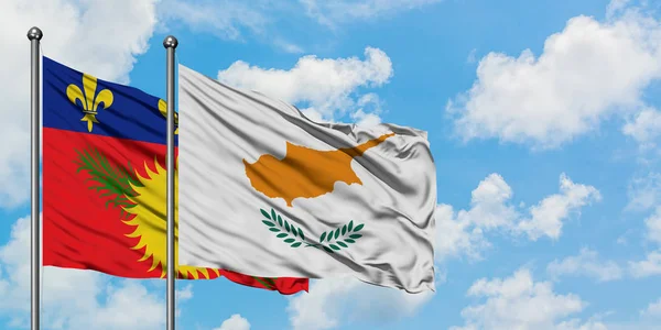 Guadalupe y la bandera de Chipre ondeando en el viento contra el cielo azul nublado blanco juntos. Concepto diplomático, relaciones internacionales . — Foto de Stock