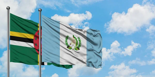 Dominica och Guatemala flagga vinka i vinden mot vit grumlig blå himmel tillsammans. Diplomatisk koncept, internationella relationer. — Stockfoto