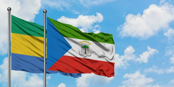 Gabón y Guinea Ecuatorial ondeando en el viento contra el cielo azul nublado blanco juntos. Concepto diplomático, relaciones internacionales . — Foto de Stock