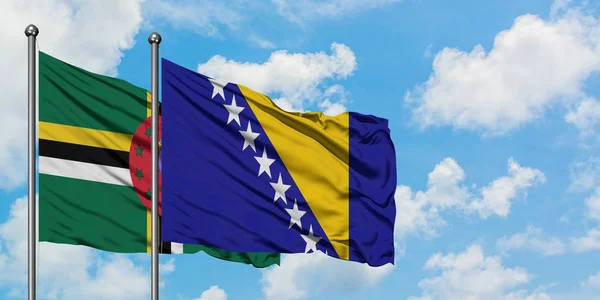 Bandera de Dominica y Bosnia Herzegovina ondeando en el viento contra el cielo azul nublado blanco juntos. Concepto diplomático, relaciones internacionales . — Foto de Stock