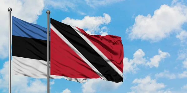 Estónia e Trinidad E Tobago bandeira acenando no vento contra branco céu azul nublado juntos. Conceito de diplomacia, relações internacionais . — Fotografia de Stock