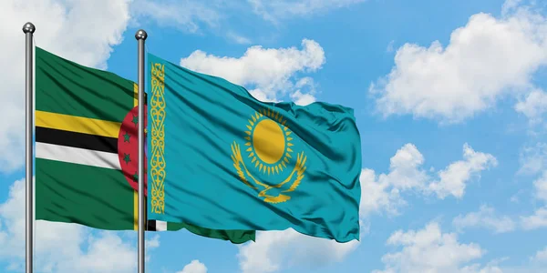 Dominica och Kazakstan flagga vifta i vinden mot vit grumlig blå himmel tillsammans. Diplomatisk koncept, internationella relationer. — Stockfoto