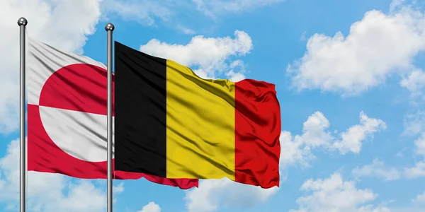 Bandera de Groenlandia y Bélgica ondeando en el viento contra el cielo azul nublado blanco juntos. Concepto diplomático, relaciones internacionales . — Foto de Stock