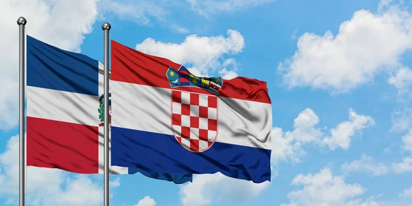 Dominikanische Republik und Kroatien schwenken gemeinsam die Flagge im Wind vor dem wolkenverhangenen blauen Himmel. Diplomatie-Konzept, internationale Beziehungen. — Stockfoto