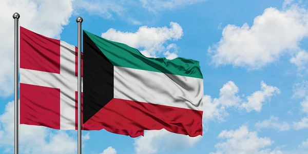 Bandera de Dinamarca y Kuwait ondeando en el viento contra el cielo azul nublado blanco juntos. Concepto diplomático, relaciones internacionales . — Foto de Stock