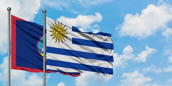 Η σημαία του Γκουάμ και της Ουρουγουάης κουνώντας τον άνεμο ενάντια στον λευκό συννεφιασμένο γαλάζιο ουρανό μαζί. Φιλοσοφία της διπλωματίας, διεθνείς σχέσεις. — Φωτογραφία Αρχείου